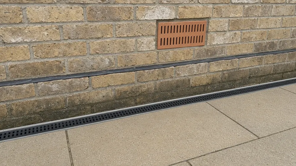 Example image: a patio edge kept below an airbrick with a channel drain